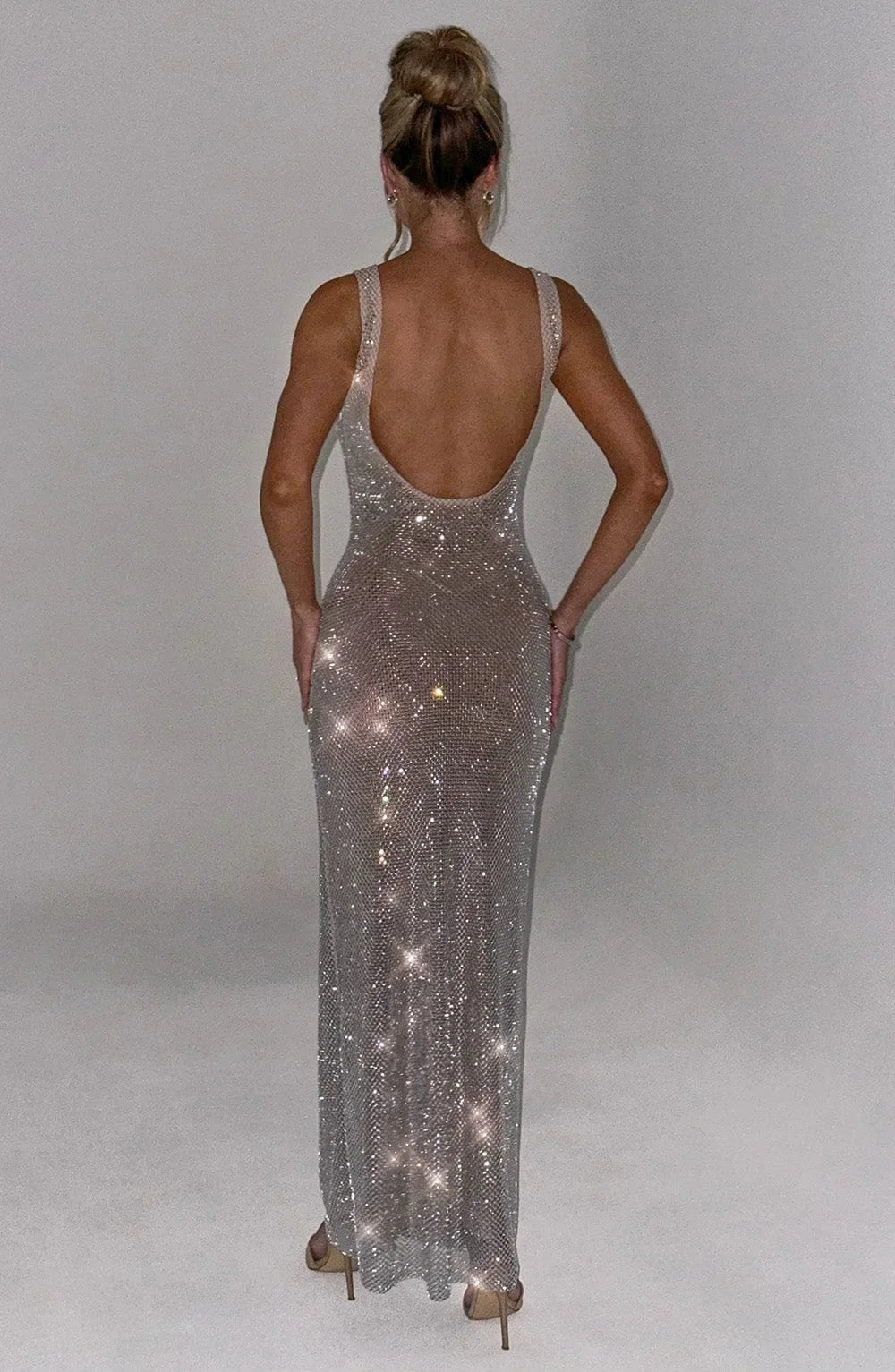 Robe longue argentée sans manches en maille ajustée, idéale pour des soirées, avec un design élégant et fluide.