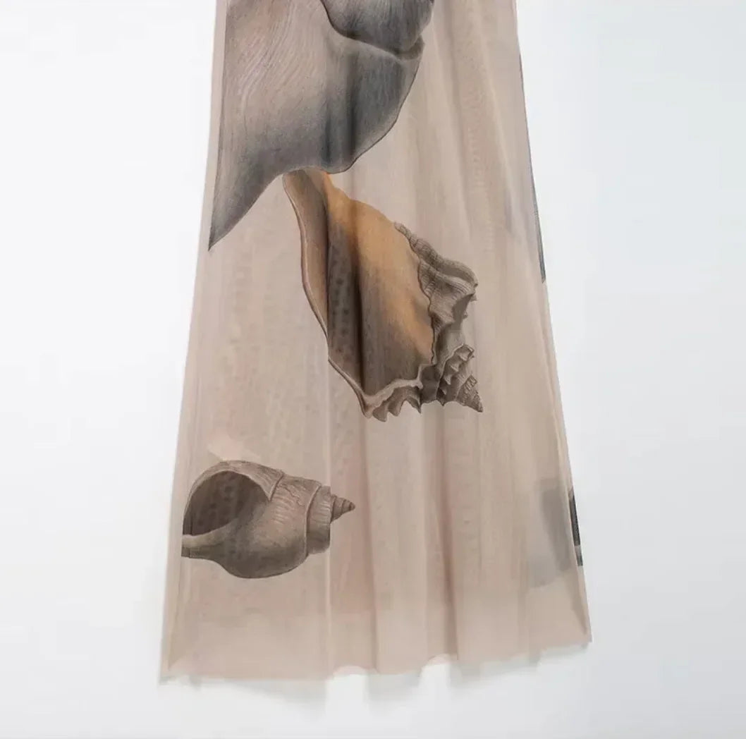 Robe longue beige à imprimé coquillage, ajustée, sans manches, col haut, en tissu léger parfait pour les soirées estivales.