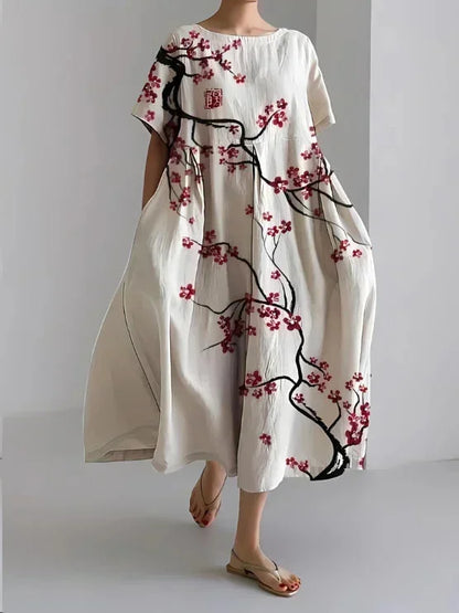 Robe maxi ample à fleurs cerisier, manches courtes, en viscose douce, avec poches pratiques de chaque côté.