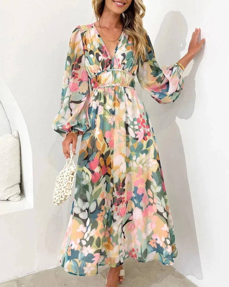 Robe longue fleurie à manches longues, col en V, en tissu fluide avec taille cintrée, idéale pour un mariage au printemps.
