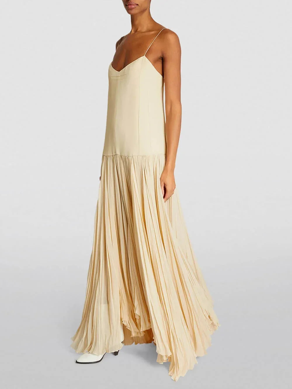 Robe longue ivoire sans manches, plissée avec bretelles fines, idéale pour des soirées d'été. Matière légère et fluide.