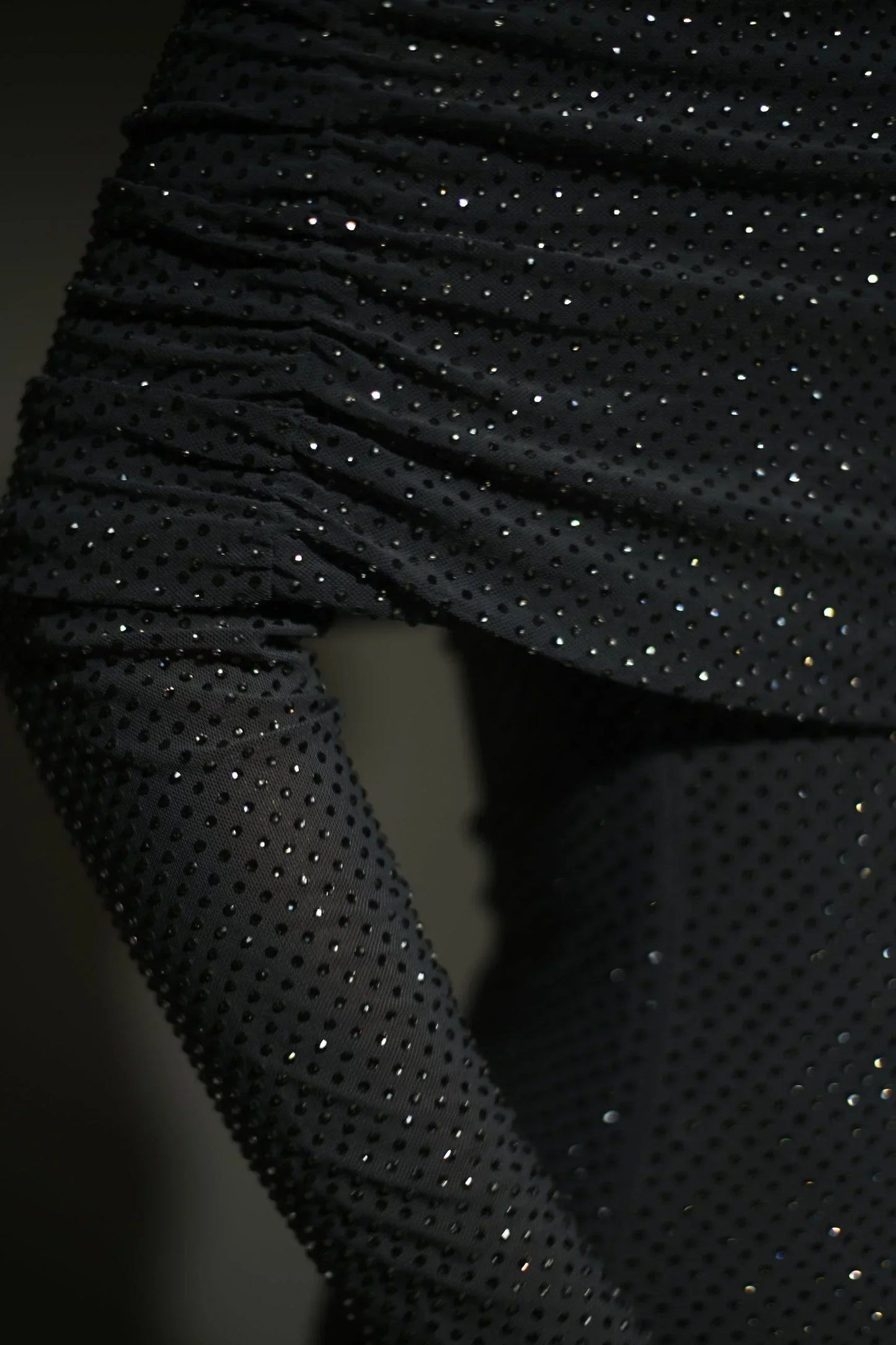 Robe longue longue scintillante avec épaules dénudées, manches longues et détails brillants en tissu léger et fluide.