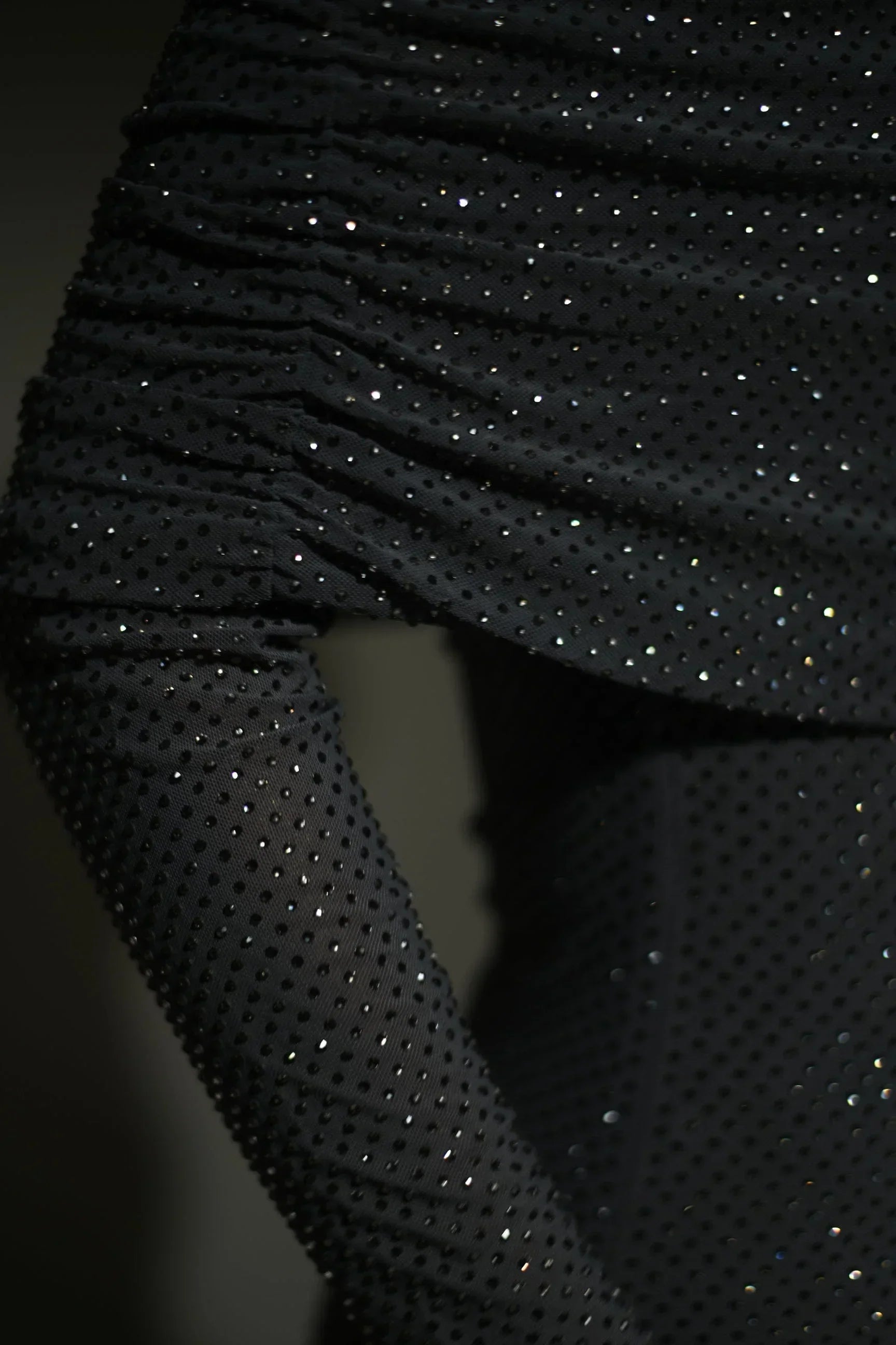 Robe longue longue scintillante avec épaules dénudées, manches longues et détails brillants en tissu léger et fluide.