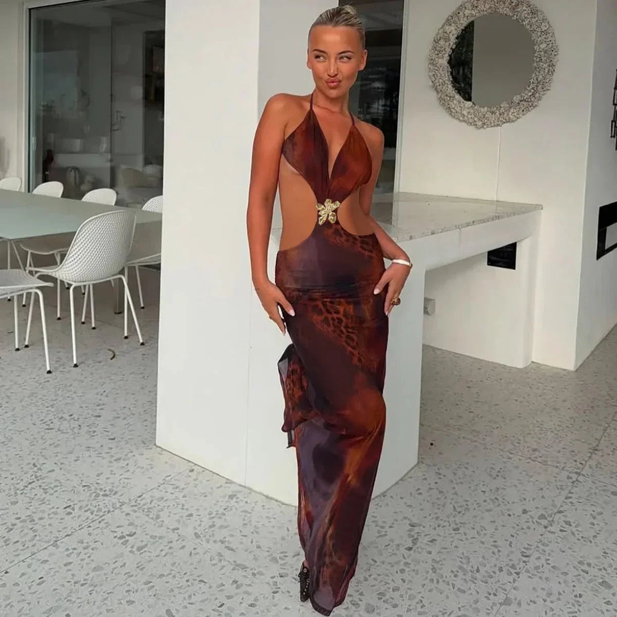 Robe longue marron ajustée en tissu léger, avec des détails dorés et découpes élégantes, idéale pour une soirée.