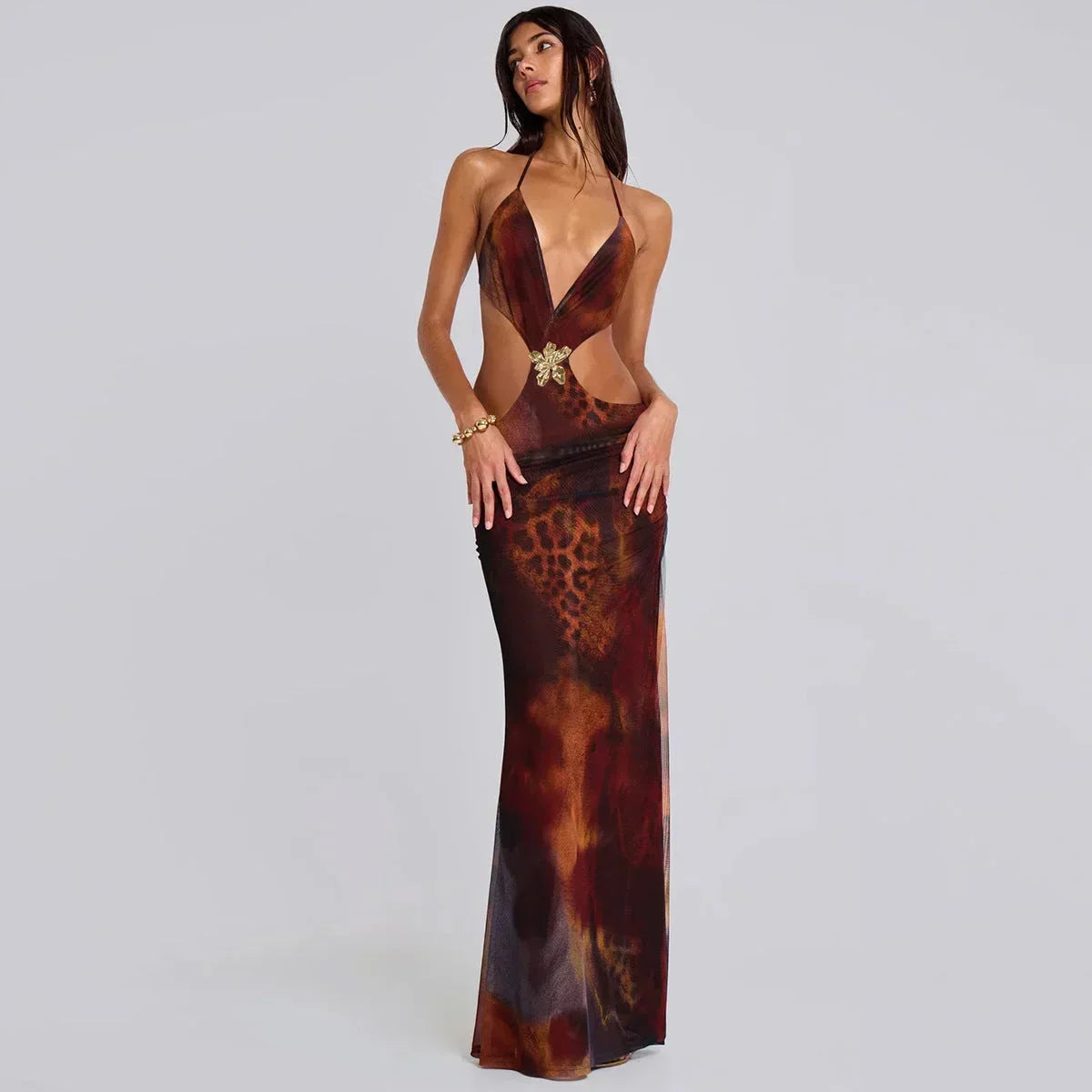 Robe longue marron ajustée avec détails dorés et découpes, tissu fluide idéale pour soirées élégantes.