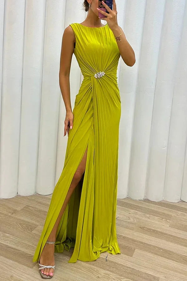 Robe longue plissée en tissu léger, fente sur le côté, ornée d'une broche élégante pour un style chic lors des soirées.