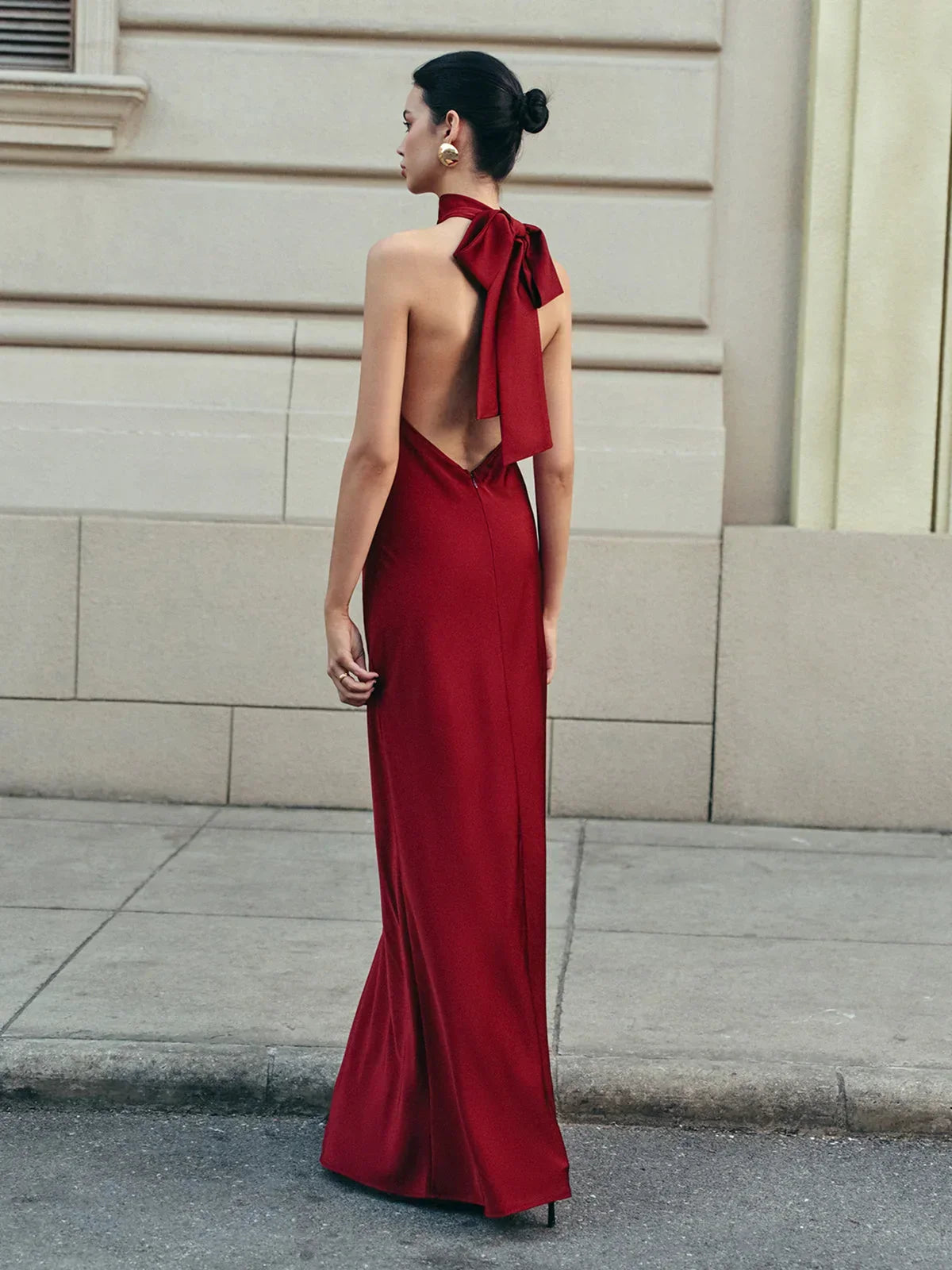 Robe longue rouge avec dos nu, nœud traînant et effet satin, idéale pour des soirées élégantes.