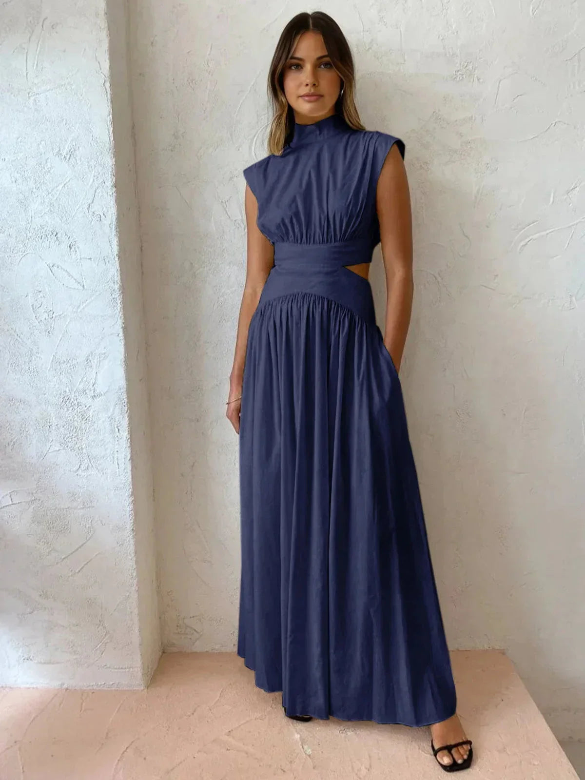 Robe longue sans manches en tissu léger, col montant, avec découpes sur les côtés, idéale pour une soirée estivale.