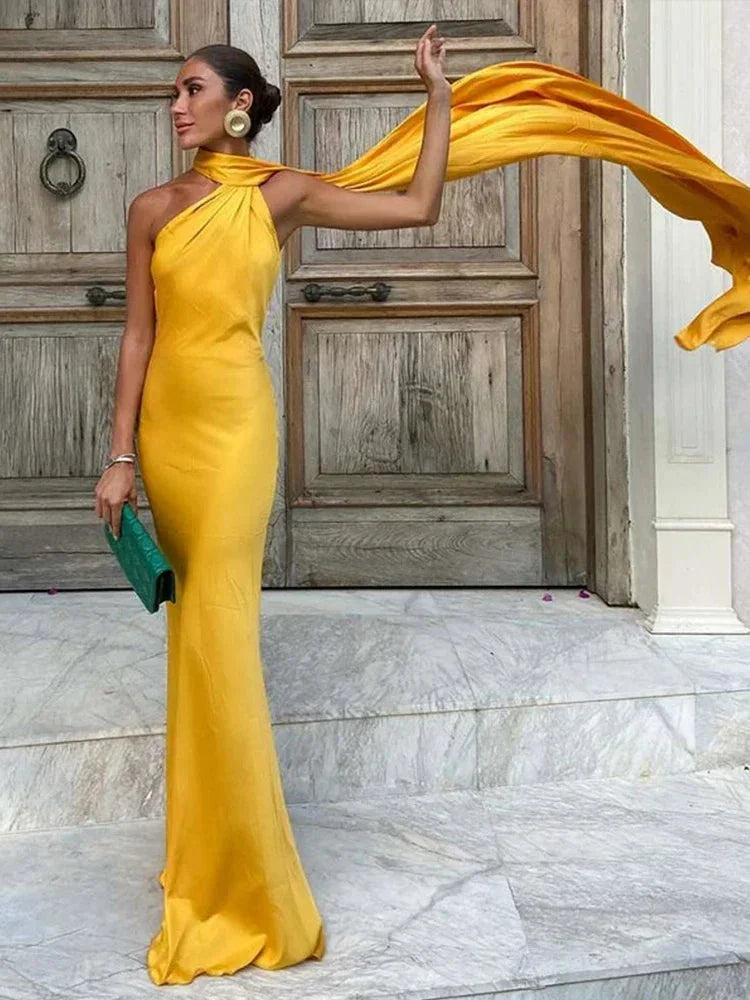 Robe longue satinée à une épaule avec cape, offrant une coupe élégante et un tissu doux au toucher.