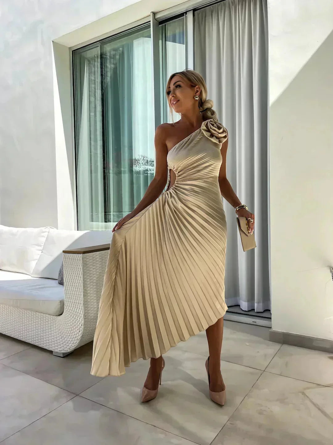 Robe midi asymétrique en tissu plissé rose, avec une découpe élégante et un design fluide pour un look moderne.