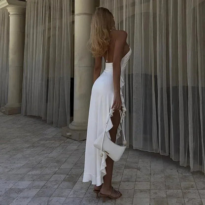 Robe midi blanche asymétrique sans manches en tissu fluide avec col licou et volants pour soirées d'été.