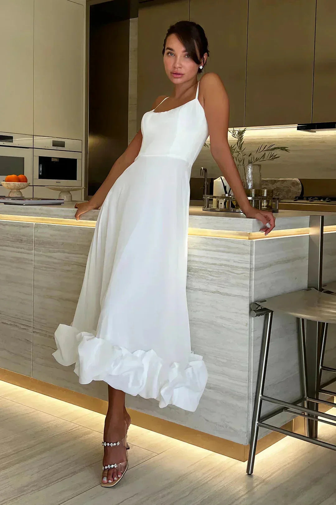 Robe midi blanche à bretelles fines, en coton léger, ornée de volants pour une touche estivale délicate.