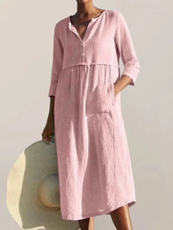 Robe midi rose femme avec col en V, poches pratiques et manches 3/4, en tissu léger et fluide pour un confort quotidien.