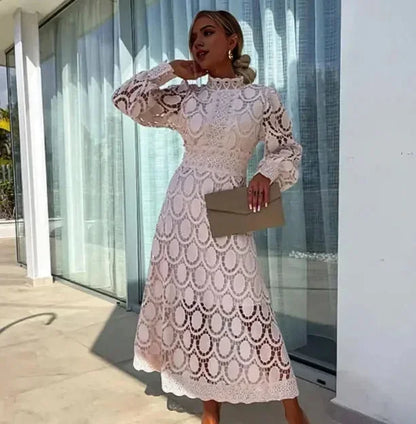 Robe midi blanche en dentelle, manches longues, avec un design élégant et ajouré, parfaite pour les occasions spéciales.