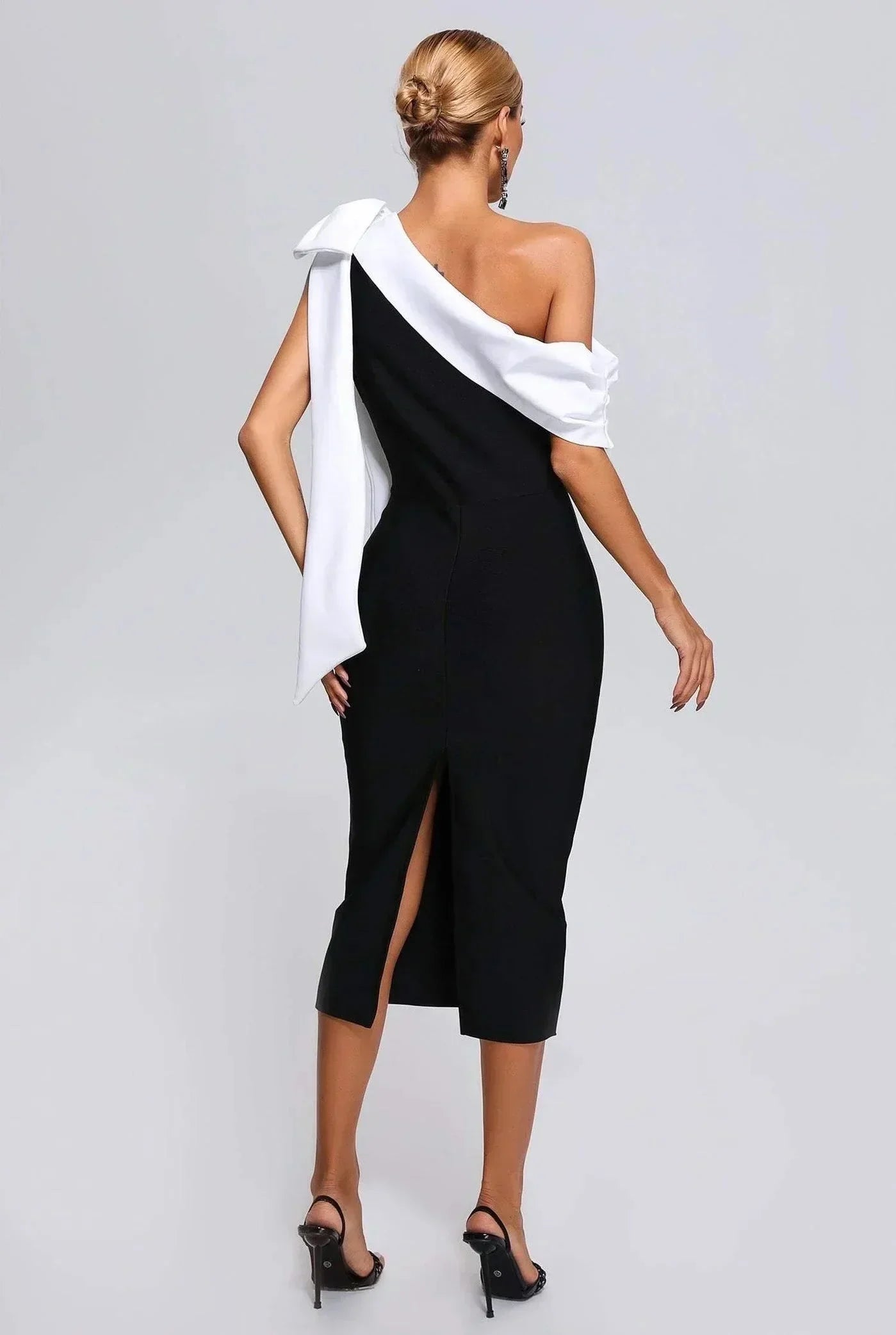 Robe midi noire et blanche, asymétrique à une épaule, en tissu léger avec nœud décoratif et coupe fluide.