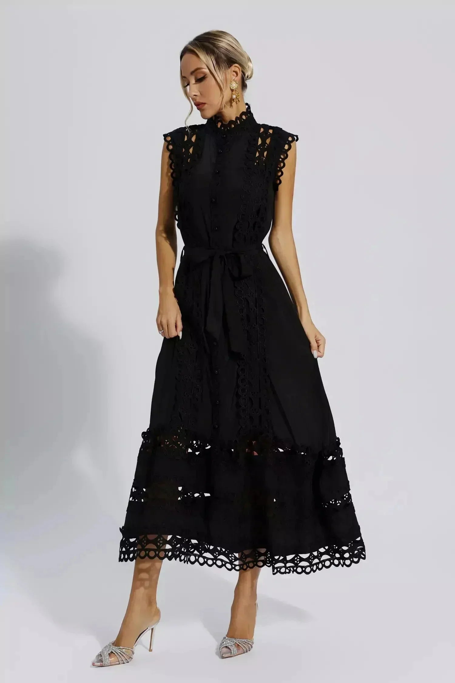 Robe midi noire sans manches, en tissu léger, avec dentelle délicate et ceinture assortie pour un ajustement chic.