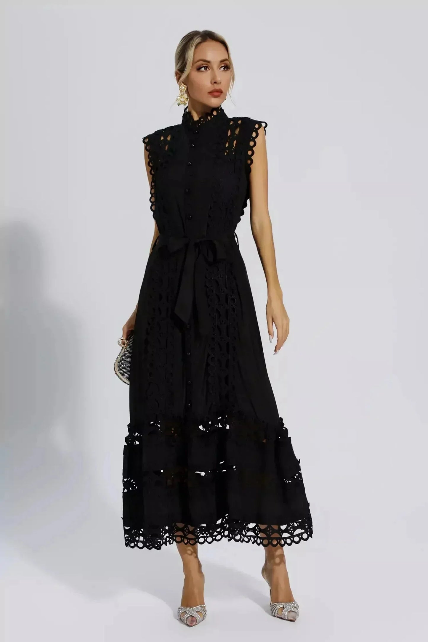 Robe midi noire sans manches en tissu léger, ornée de dentelle délicate et ceinture assortie pour une silhouette élégante.