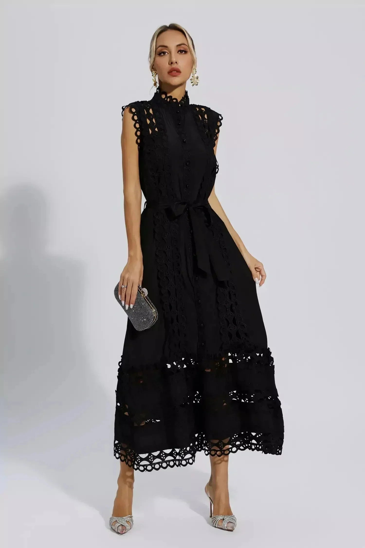 Robe midi noire sans manches en tissu léger, ornée de dentelle délicate et d'une ceinture ajustable à la taille.