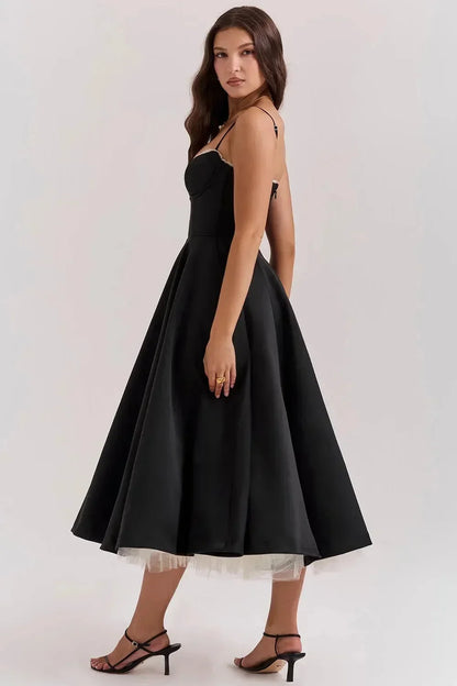 Robe midi satinée noire avec tulle crème, à bretelles fines et design élégant pour soirées. Matériau doux et fluide.