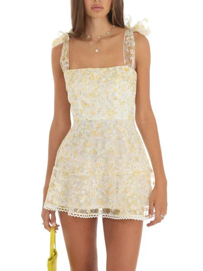 Robe courte A-ligne en tissu léger, détails en dentelle délicate et nœuds sur les épaules, idéale pour une soirée d'été.