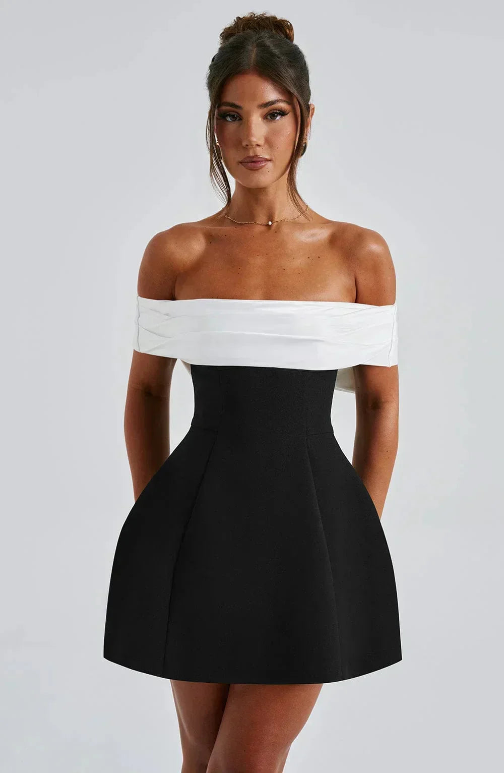 Robe courte bicolore en coton, épaules dénudées, avec un nœud blanc, parfaite pour les soirées. Design chic et confortable.