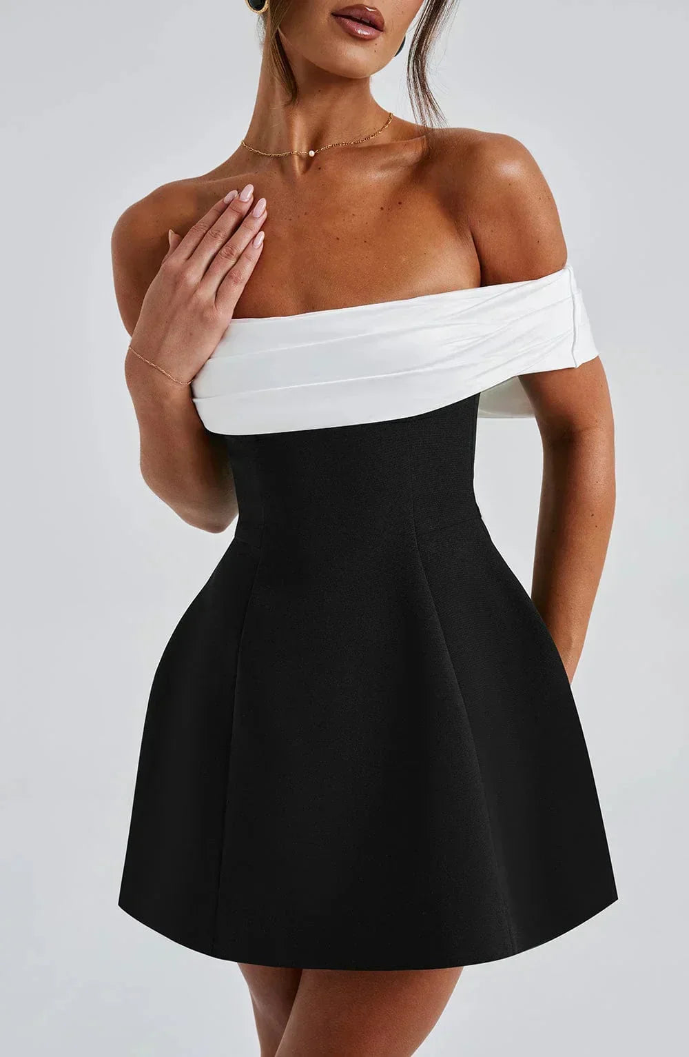 Robe courte bicolore avec épaules dénudées et nœud blanc, en tissu léger, parfaite pour les soirées estivales.