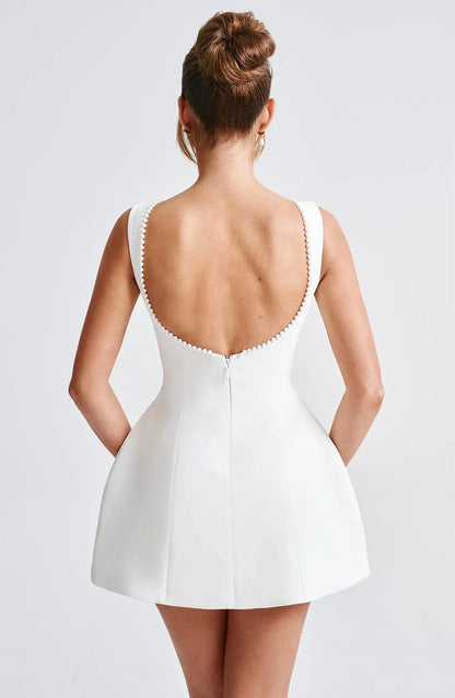 Robe courte dos nu en tissu léger, ornée de perles et d’un gros nœud, idéale pour une soirée, disponible en plusieurs couleurs.