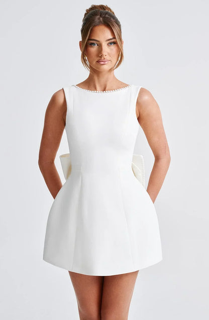 Robe courte dos nu ornée de perles et d'un gros nœud, en tissu léger, parfaite pour des soirées. Disponible en plusieurs…