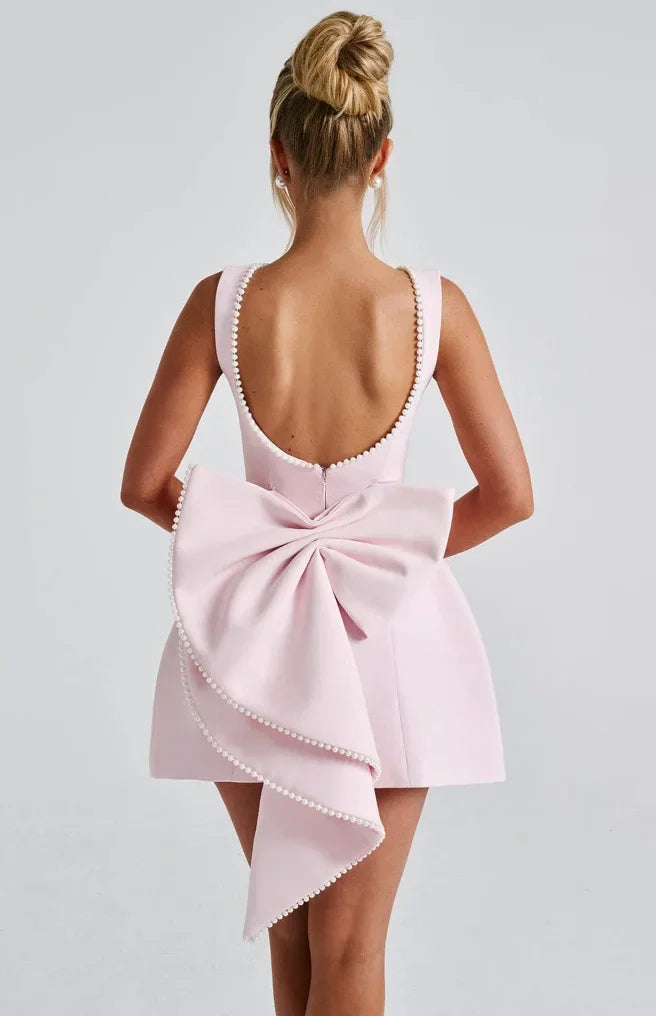 Robe courte dos nu avec perles décoratives et un gros nœud, en tissu léger, parfaite pour les soirées estivales.