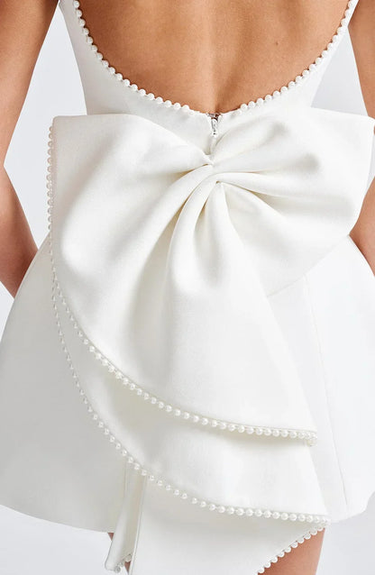 Robe courte dos nu avec perles et gros nœud, en tissu léger, idéale pour soirées, disponible en plusieurs couleurs.
