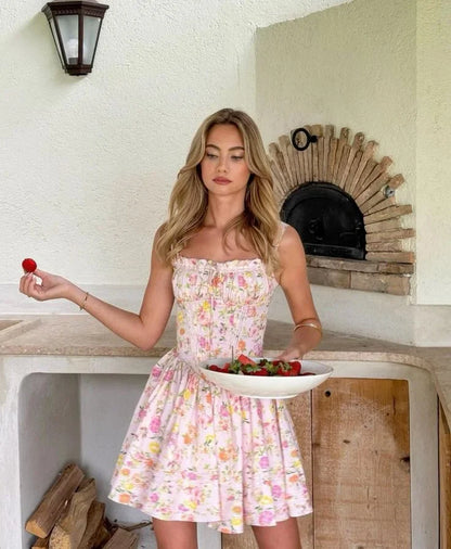 Robe courte fleurie rose à corset, fabriquée en coton léger, avec bretelles larges et motifs floraux pour un style estival.