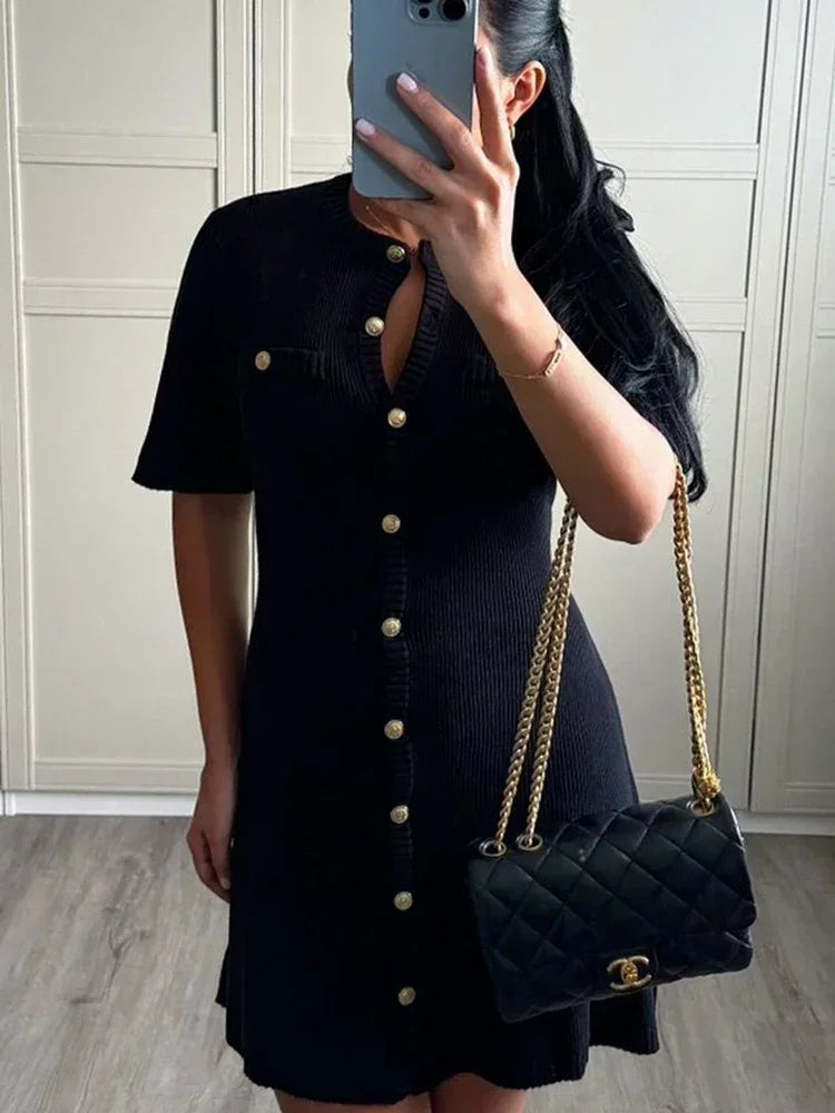 Robe mini en maille noire, boutons décoratifs sur le devant, manches courtes et coupe moderne pour un style décontracté.