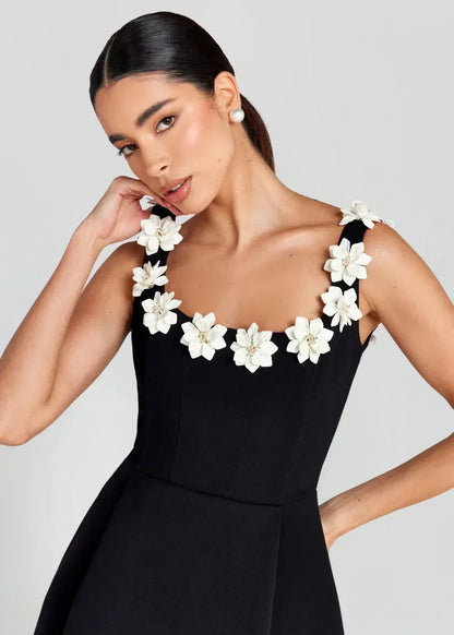Robe courte noire sans manches, en tissu léger, brodée de fleurs blanches, parfaite pour une soirée élégante.