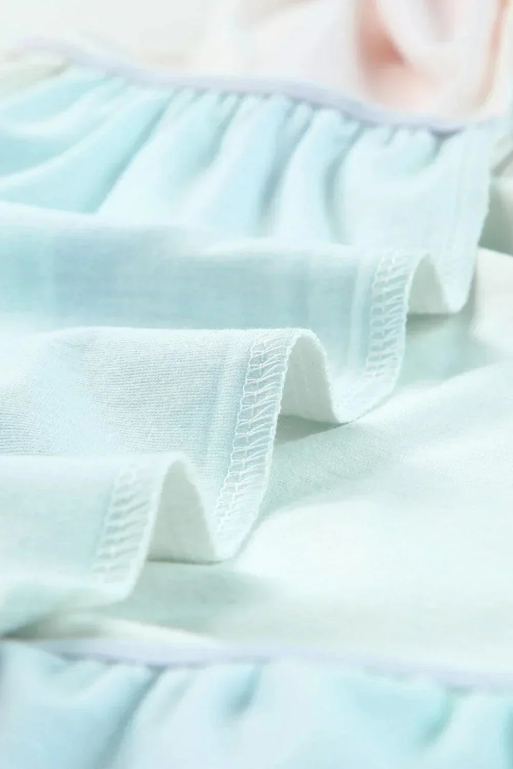 Robe courte pastel en tissu léger avec volants et manches courtes, idéale pour un look d'été décontracté à la plage.