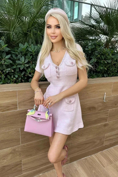 Robe courte rose en coton avec boutons, poches, manches courtes et col V, parfaite pour les journées d'été.