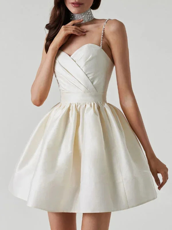 Robe courte en satin avec bretelles strass, col cœur, dos nu, disponible en plusieurs couleurs pour soirées élégantes.