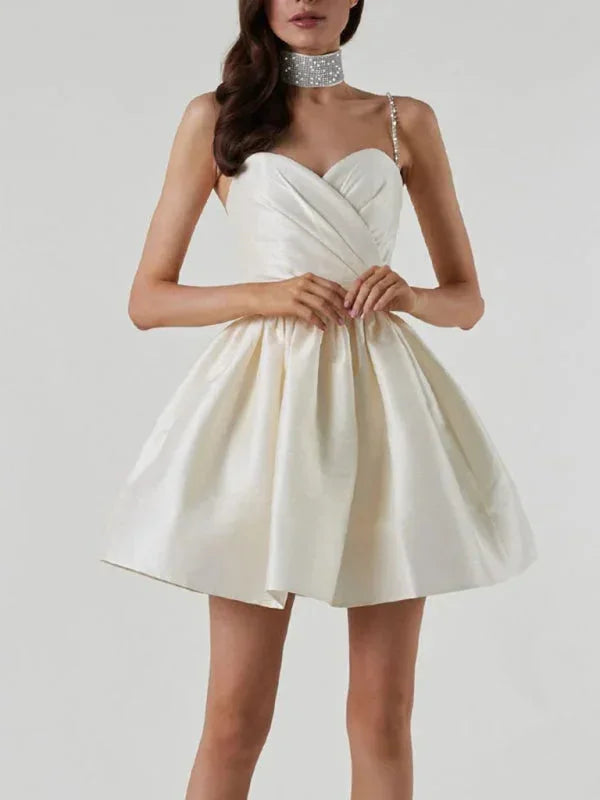 Robe courte satinée avec bretelles en strass, col cœur et dos nu, parfaite pour les soirées. Disponible en plusieurs couleurs.