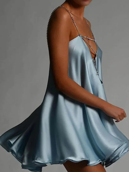 Robe courte en satin fluide avec chaînes décoratives, idéale pour une soirée élégante et confortable.