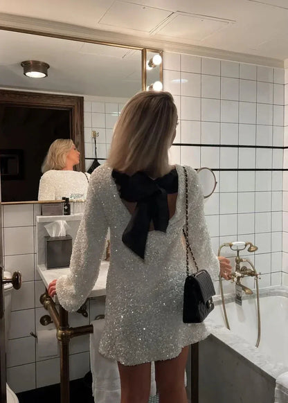 Robe courte blanche à manches longues, col chic, en tissu brillant, idéale pour des soirées élégantes.