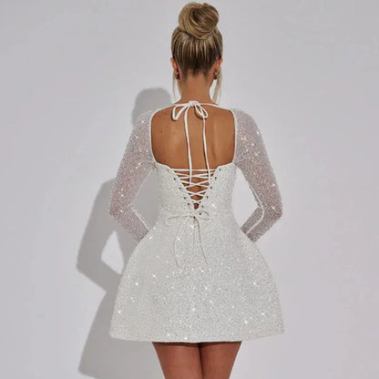 Robe courte scintillante avec manches longues transparentes, bustier carré, idéale pour soirées, en tissu léger et brillant.