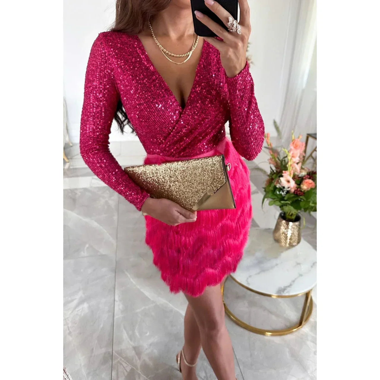 Robe courte à sequins avec un haut croisé, jupe à plumes et manches longues, idéale pour les soirées. Fabrication en polyester.