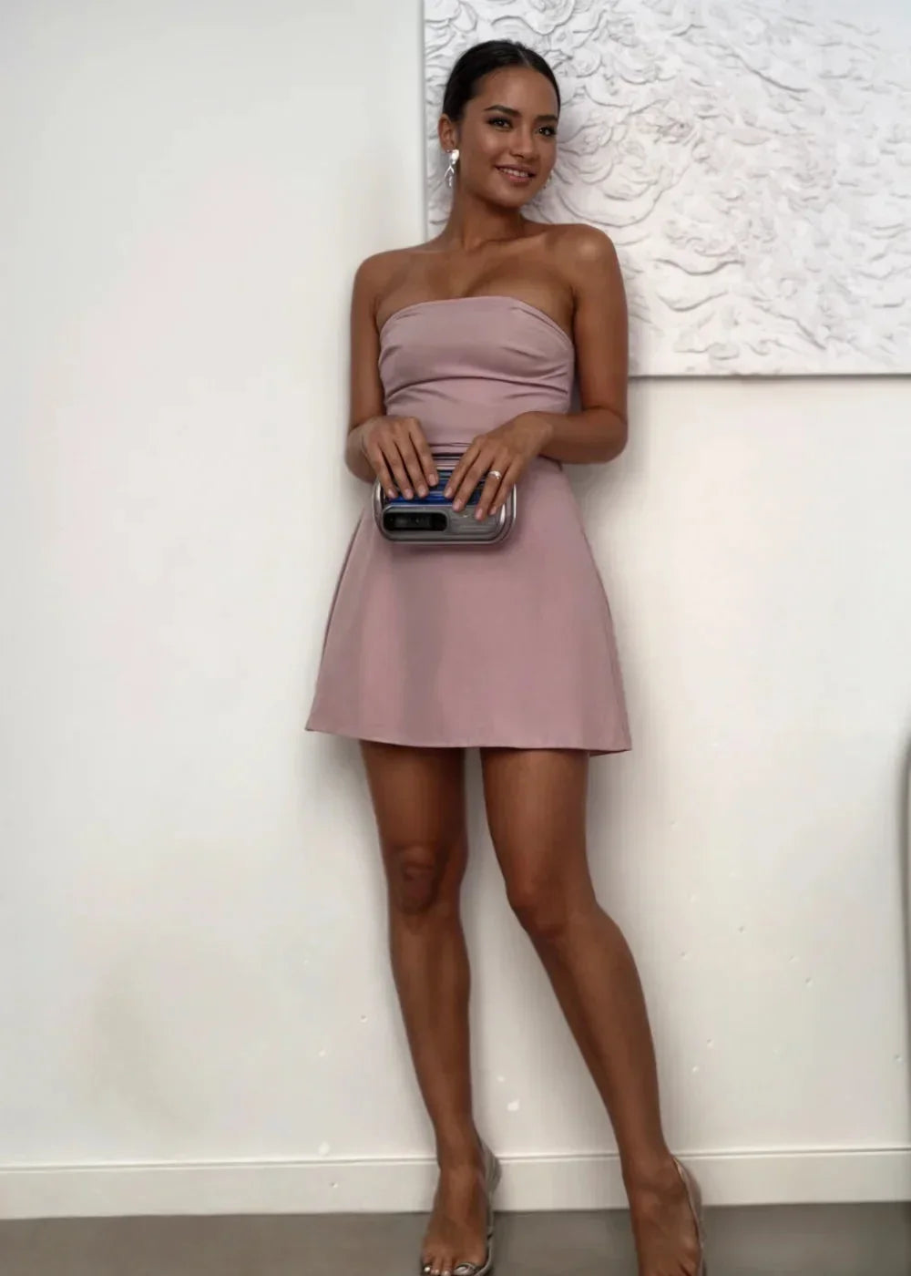 Robe courte rose poudré sans bretelles, coupe ajustée, accompagnée d'une pochette assortie, en tissu léger et fluide.
