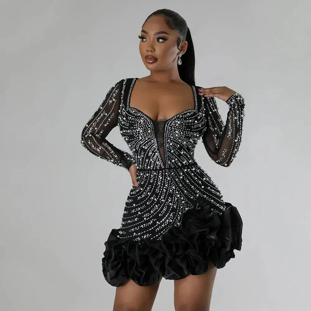 Robe courte noire à strass, manches longues, volants et décolleté plongeant, idéale pour les soirées élégantes.