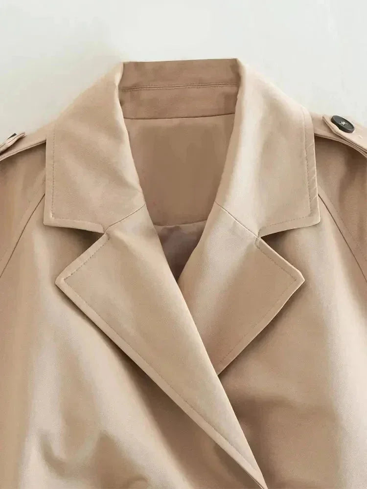 Trench court beige femme à manches longues, en tissu doux, coupe cintrée et col revers classique.