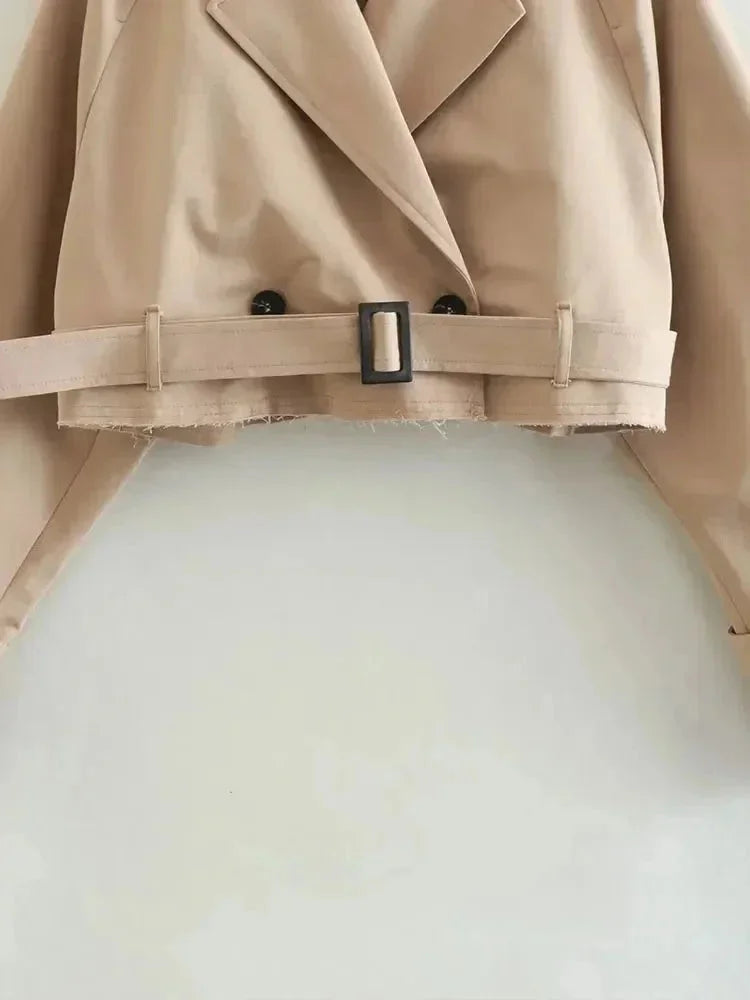 Trench court beige femme à manches longues, en tissu léger, avec un design classique pour les saisons intermédiaires.