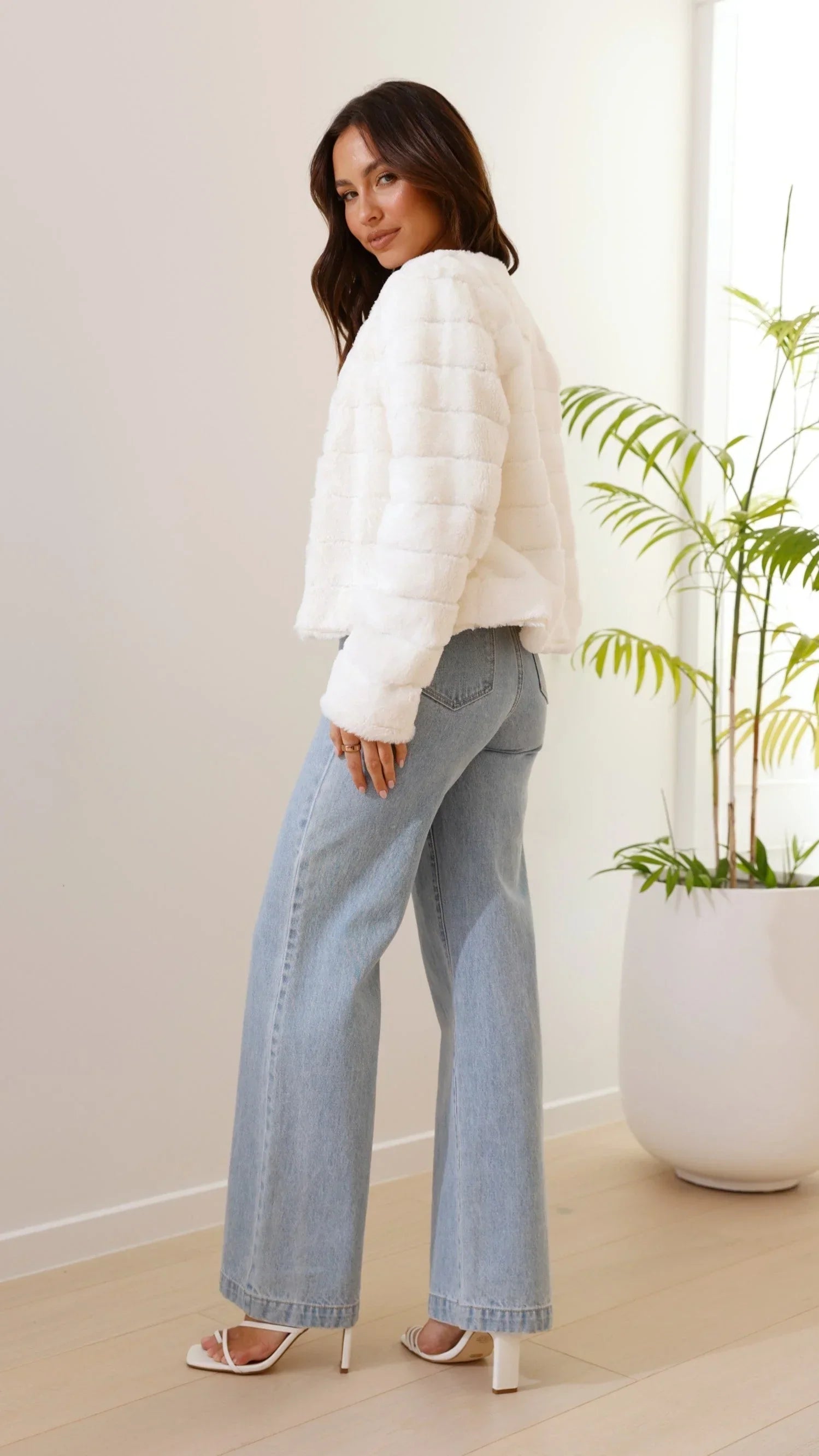Veste courte femme en fausse fourrure blanche avec col ouvert, douce et chaude, adaptée pour les journées fraîches.