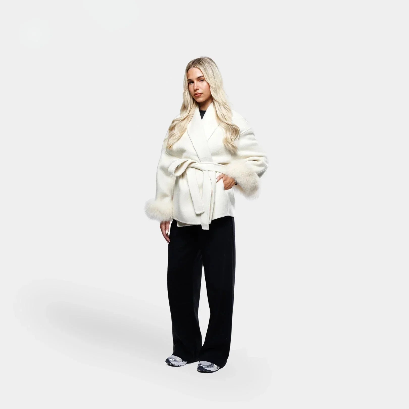 Veste blanche pour femme, ceinturée, avec manches en fourrure synthétique et coupe ajustée.