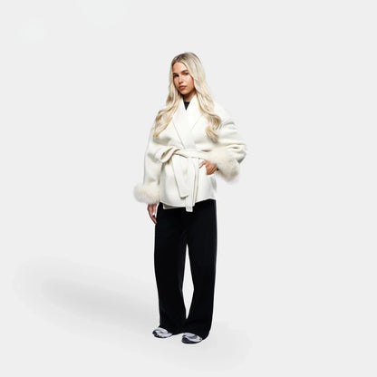 Veste blanche pour femme, ceinturée, avec manches en fourrure synthétique et coupe ajustée.