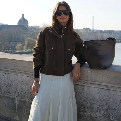 Veste femme motard kaki, en matériau résistant, avec poches avant et coupe asymétrique.