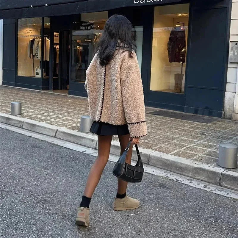Veste teddy femme beige avec coutures noires, en matériau doux, coupe confortable.